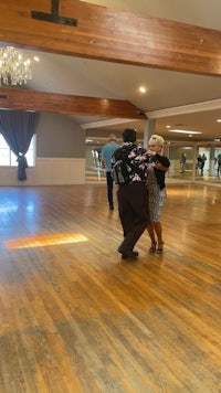 two people dancing in a large room with hardwood floors